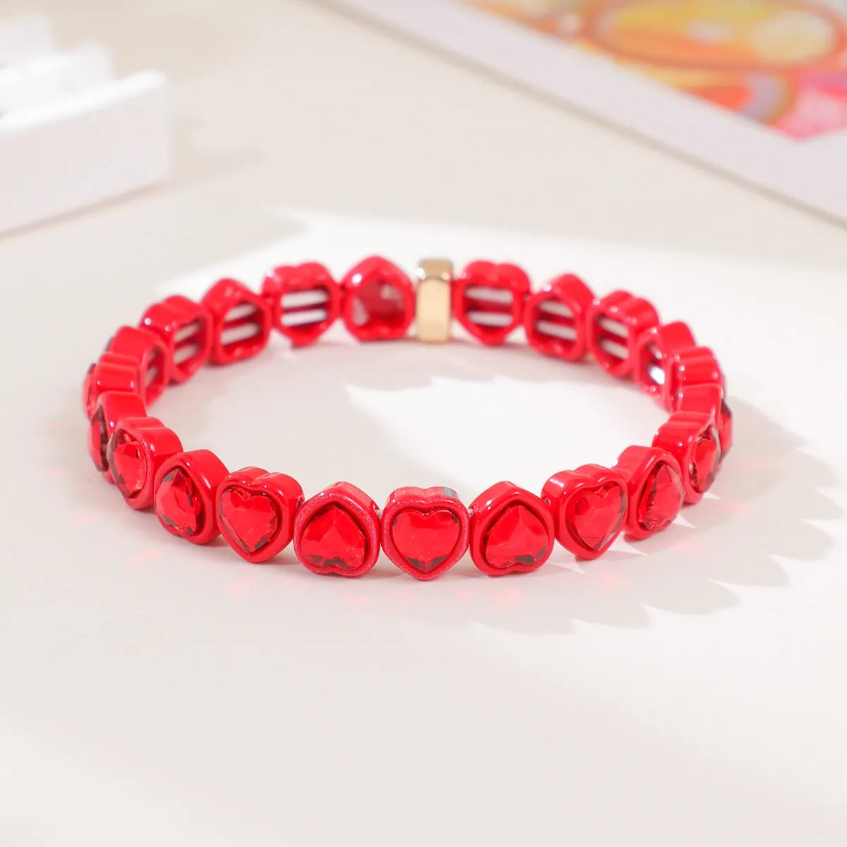 Colourful enamel finish alloy heart charm on a black stretch bracelet band.