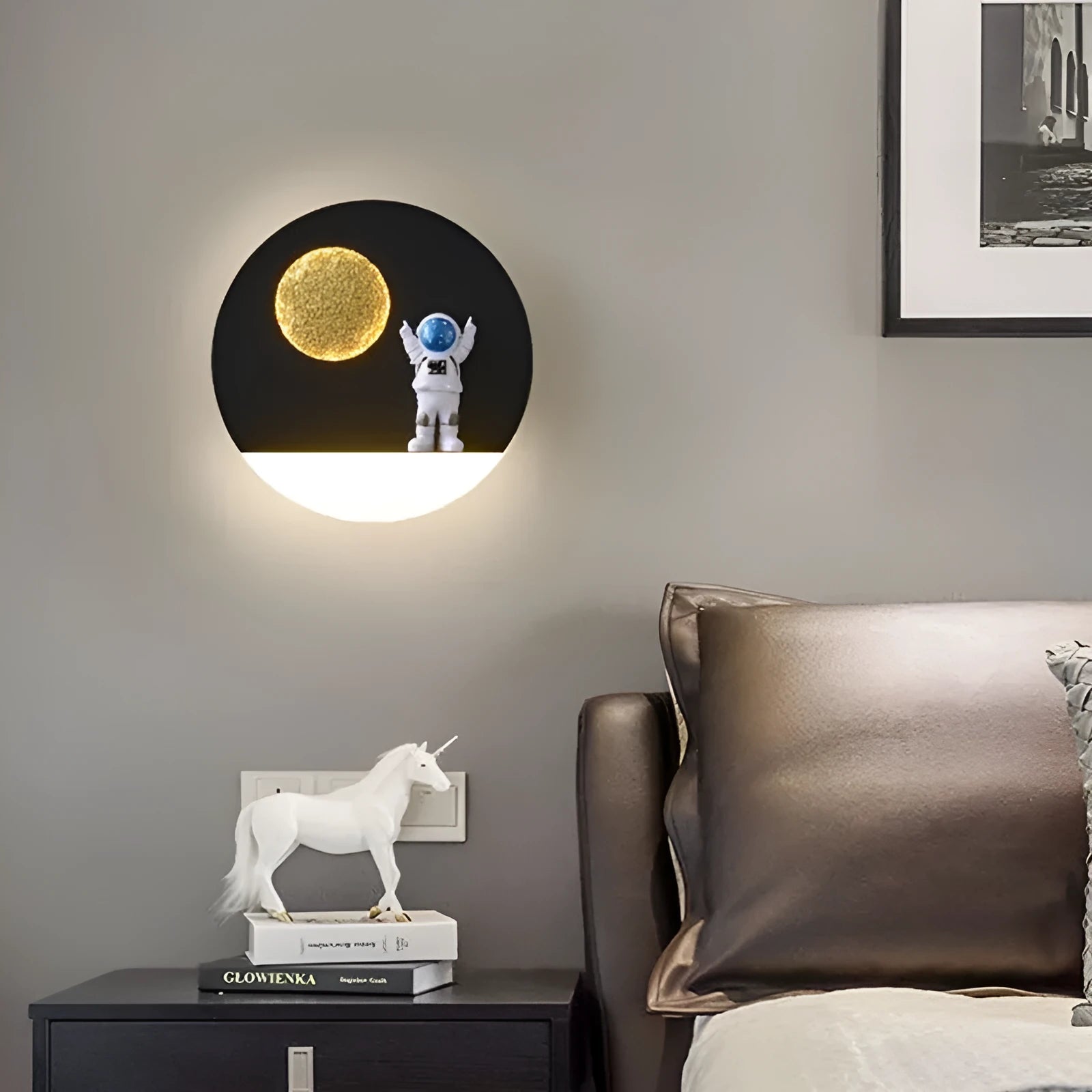 White astronaut-shaped wall lamp with a small shelf, mounted on a bedroom wall.