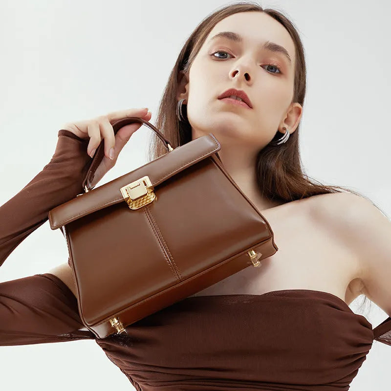Women's black leather shoulder bag with clasp closure and adjustable strap showing interior organisation