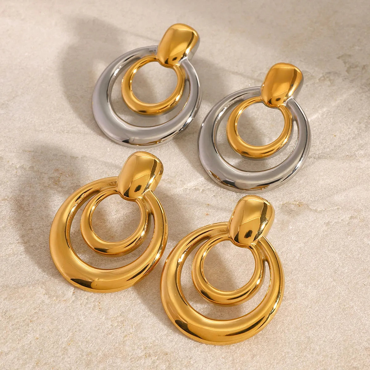 Gold-plated geometric stud earrings with hollow double-layer round design on titanium steel backing.