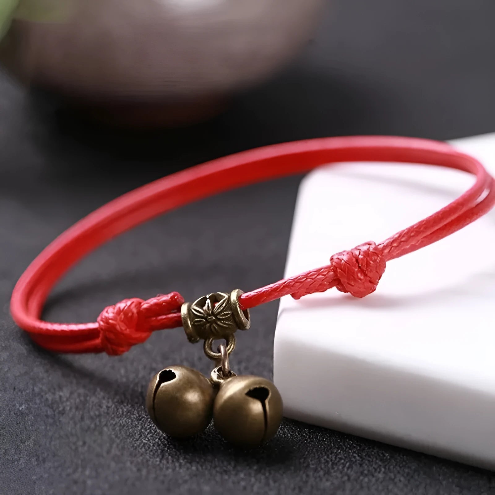 Close-up of a black nylon rope dog collar with a small brass bell and a brass buckle fastener.