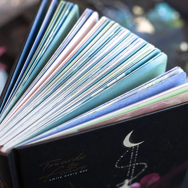 A5 notebook with luminous illustrated cover in blue, shown open on a desk.