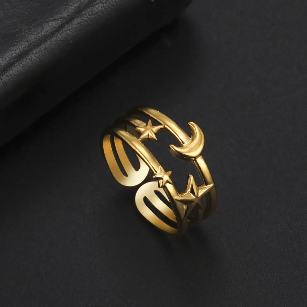 Gold electroplated stainless steel star shaped opening ring on a plain background
