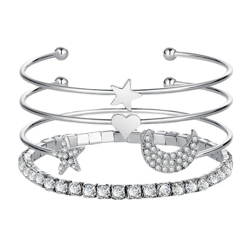 Four gold and silver metal cuff bracelets with moon and star designs on a plain background