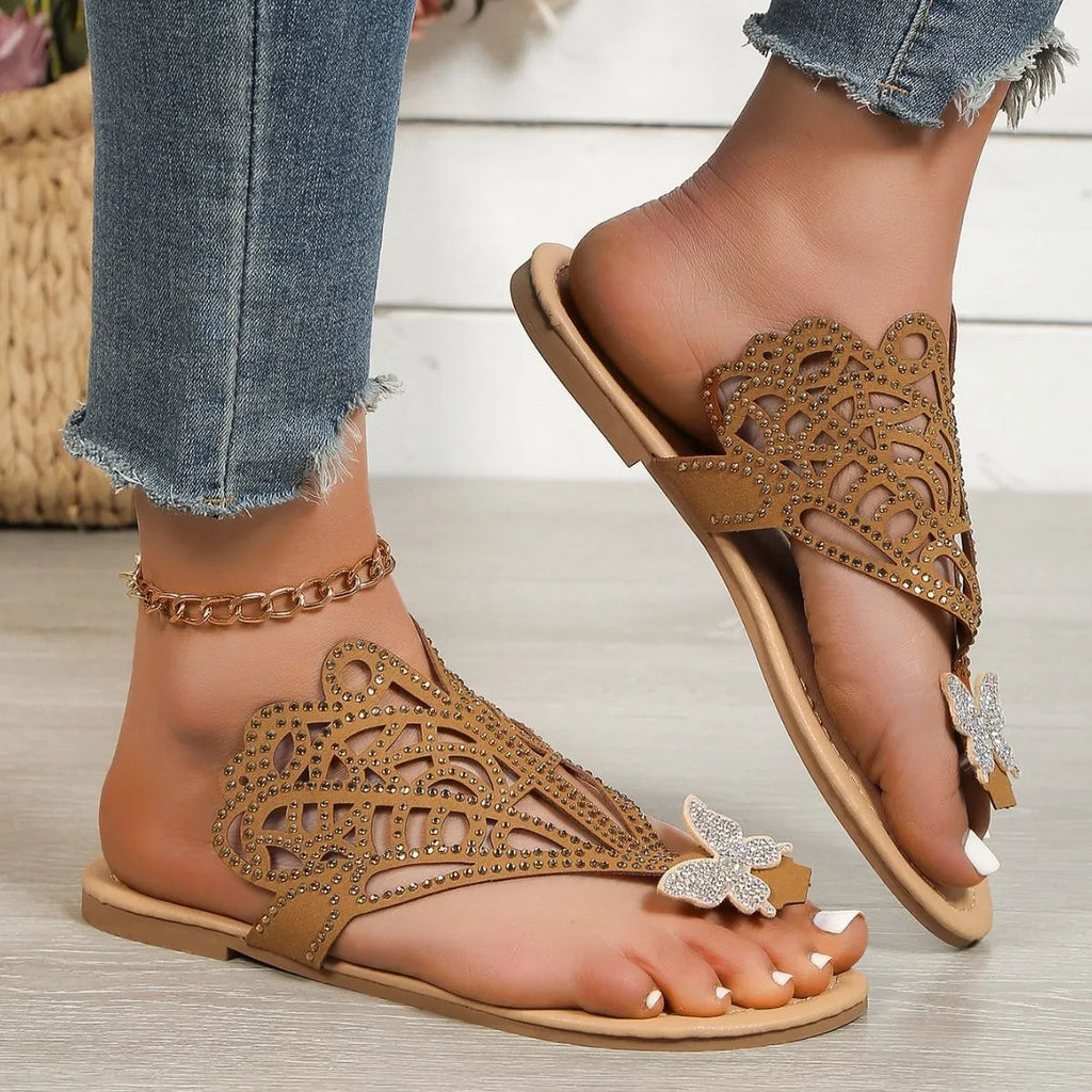 Women's black slip-on sandals with rhinestone details and flip-toe design on a white background