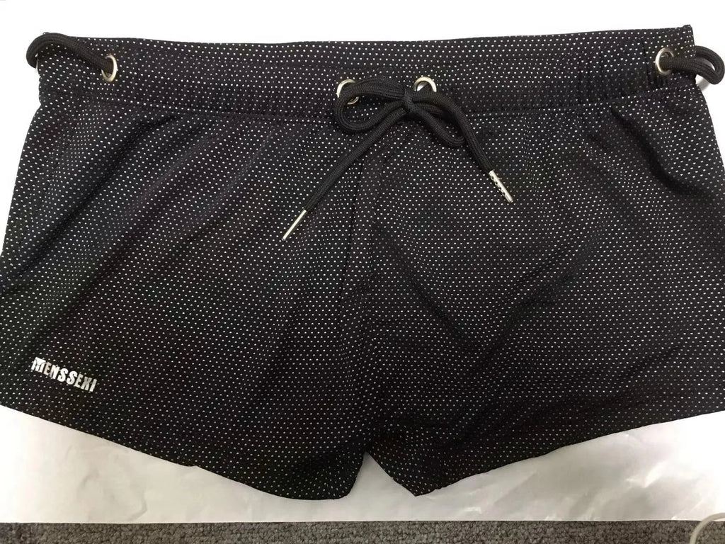 Men's solid colour lace nylon low waist boxer swimming trunks on a white background.