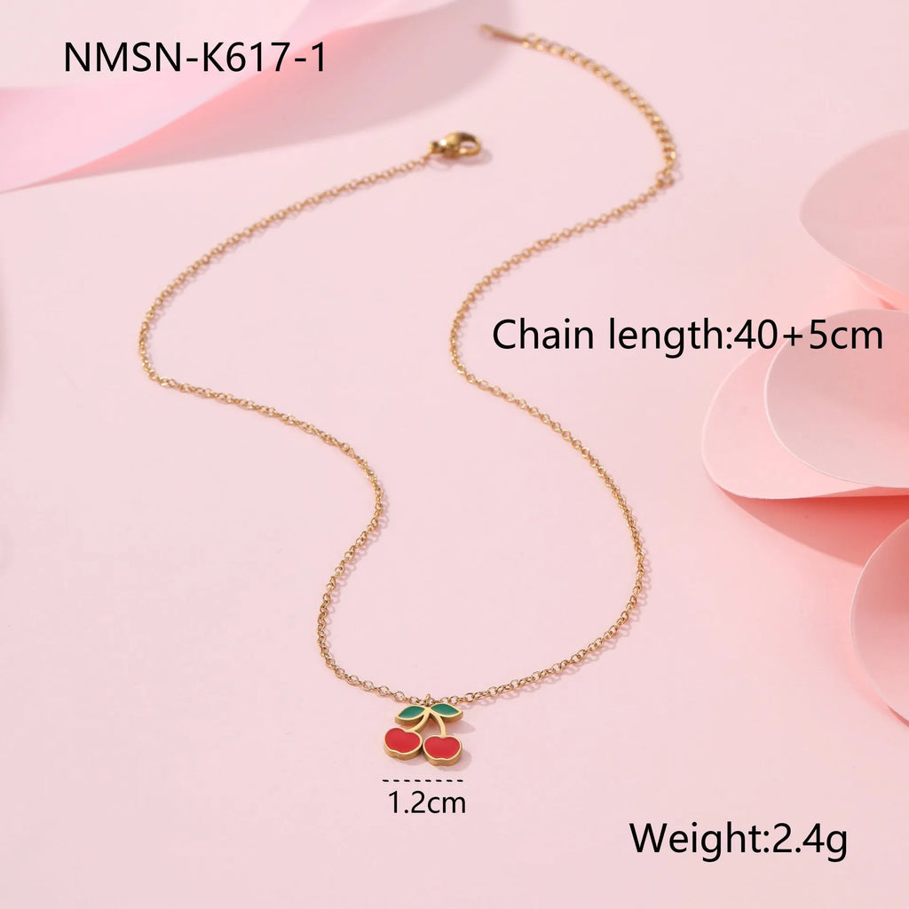 Cherry design jewellery set with gold plated necklace, bracelet, earrings, and ring on a flat surface.