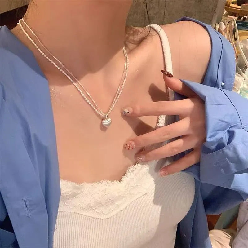 Double-layer brushed heart pendant necklace on model showing adjustable chain length