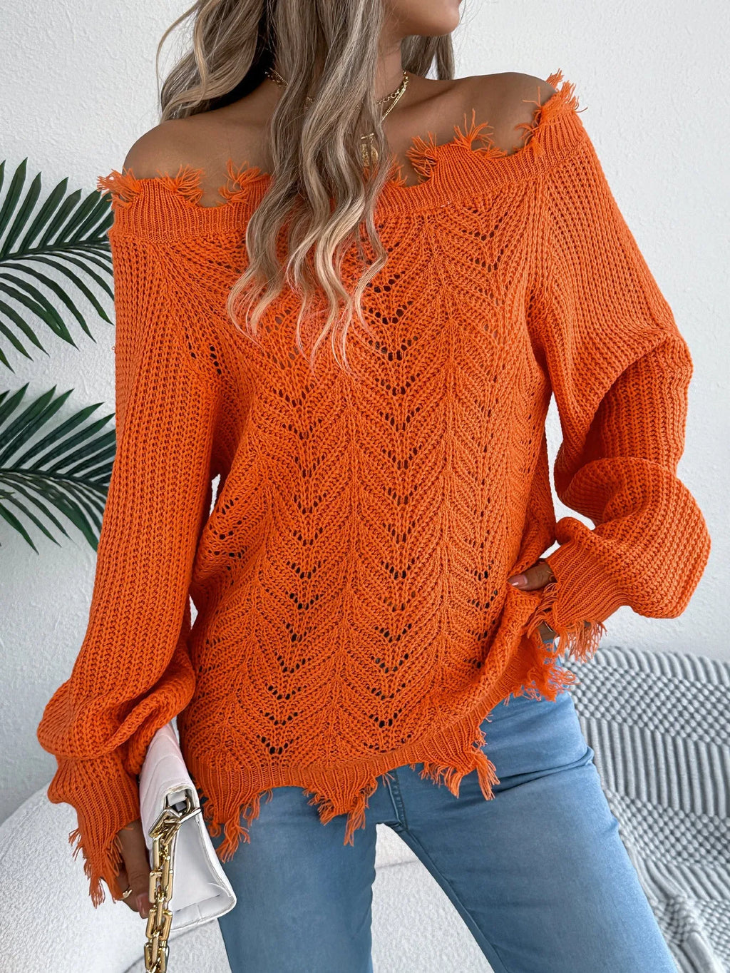 White women's pullover sweater with cut-off-the-shoulder neckline and hollow-out patterned long sleeves.