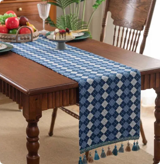 Long blue ginkgo leaf patterned table flag with tassels draped over a wooden sideboard.