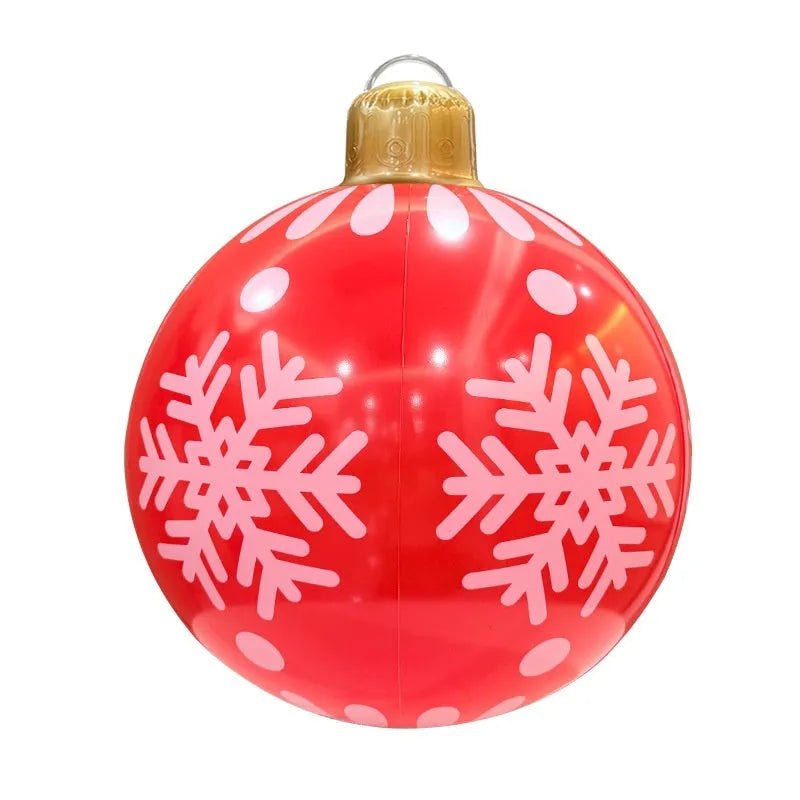 Large red inflatable Christmas ball with gold snowflake design hanging in garden with LED lights illuminated