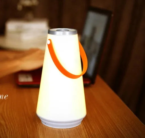 White rechargeable LED table lamp with USB cable on a wooden surface.