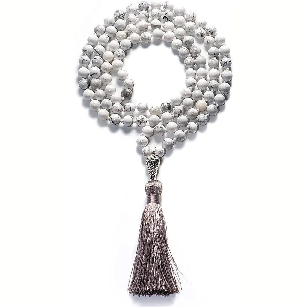 Long beaded agate and amethyst tassel necklace with geometric pendant on a neutral background.
