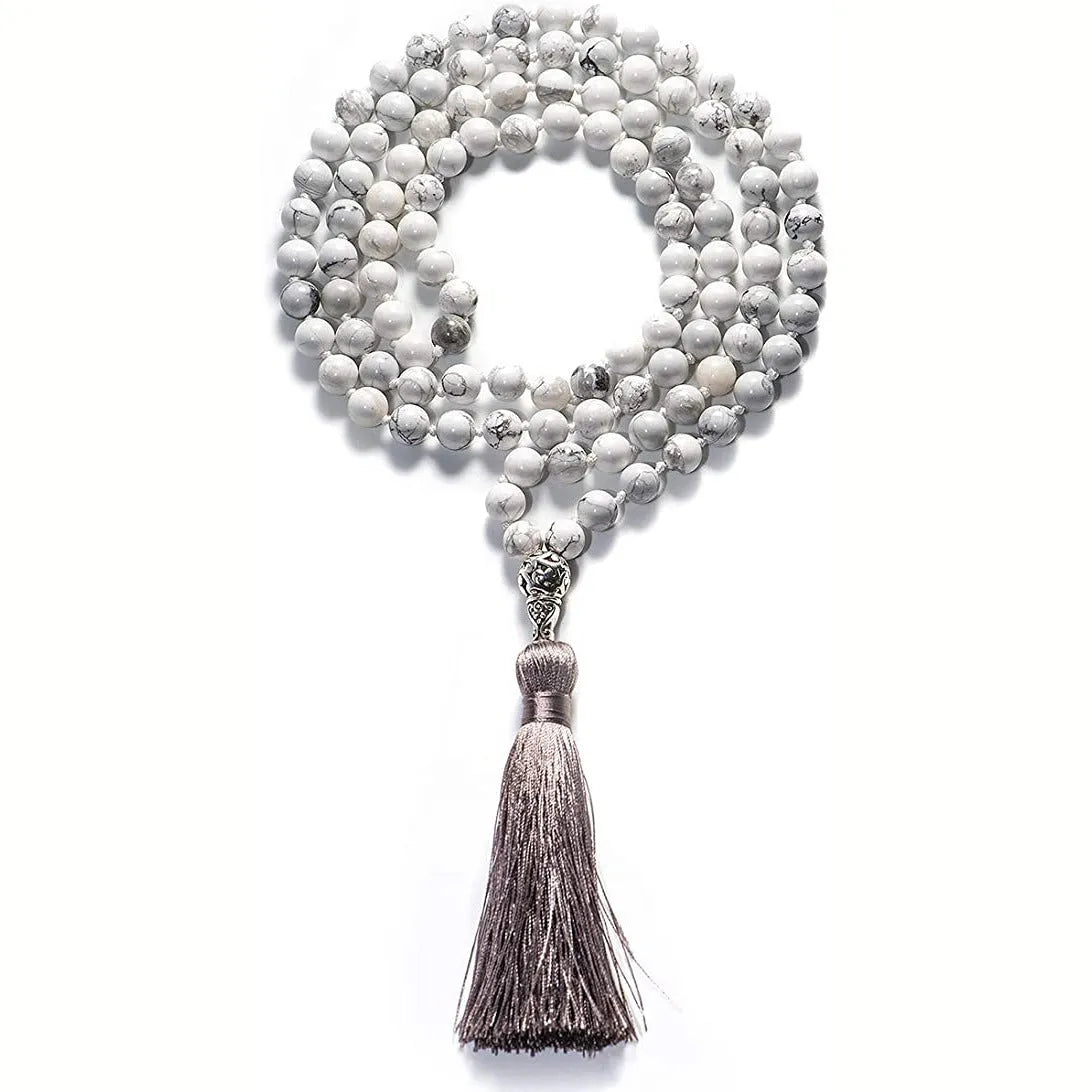 Long beaded agate and amethyst tassel necklace with geometric pendant on a neutral background.