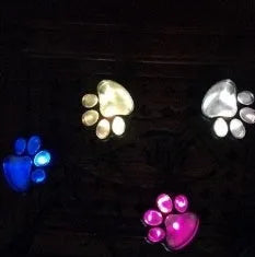 Black solar powered bear paw print garden lights with four paw design on grass