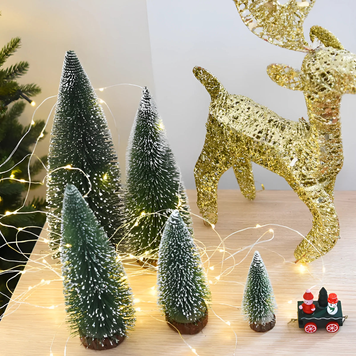 Set of artificial Christmas pine needle trees in green and white, heights 10cm to 30cm, on a tabletop