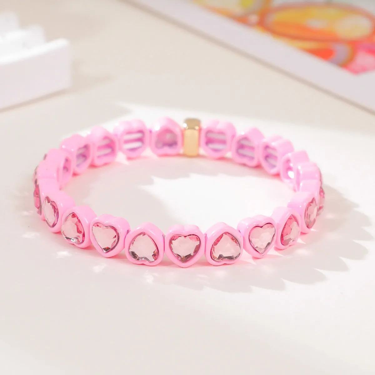 Colourful enamel finish alloy heart charm on a black stretch bracelet band.