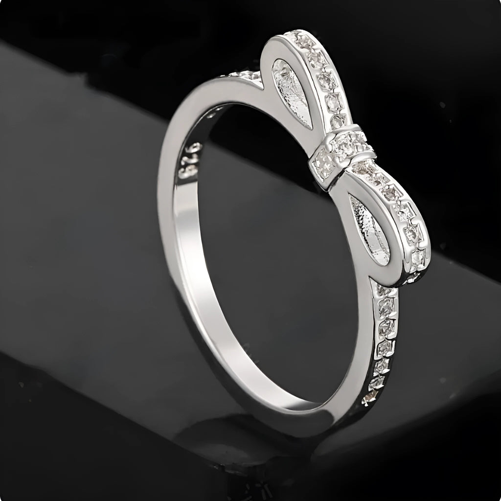 Silver-colour bow ring with zircon crystal details on a white background.