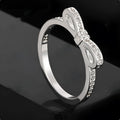 Silver-colour bow ring with zircon crystal details on a white background.