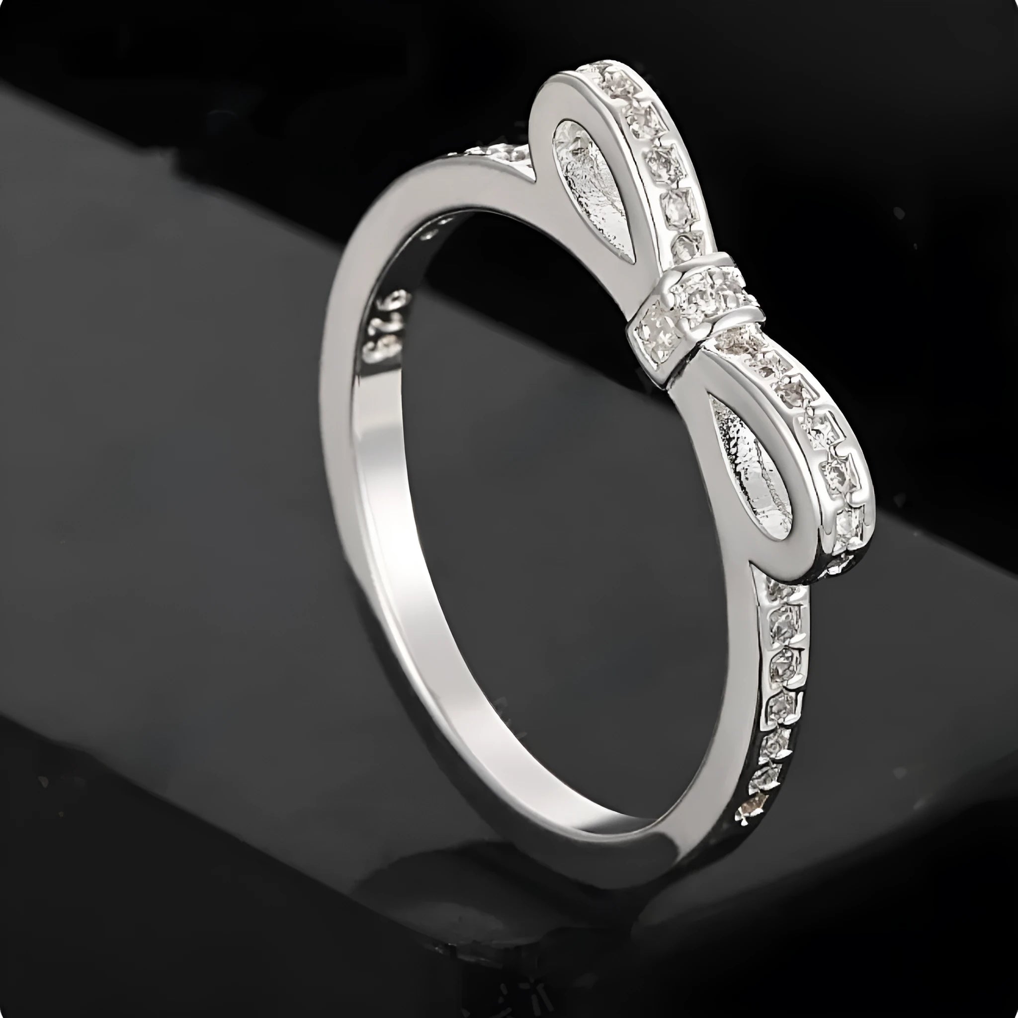 Silver-colour bow ring with zircon crystal details on a white background.