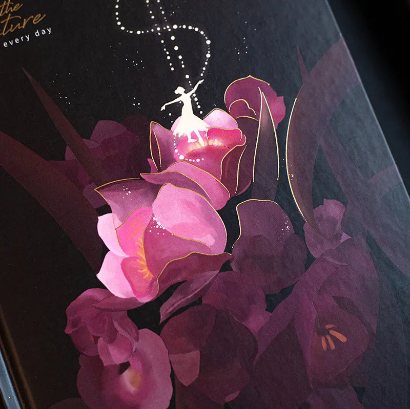 A5 notebook with luminous illustrated cover in blue, shown open on a desk.
