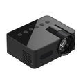 YT100 black mini portable projector on a desk with remote control and USB cable