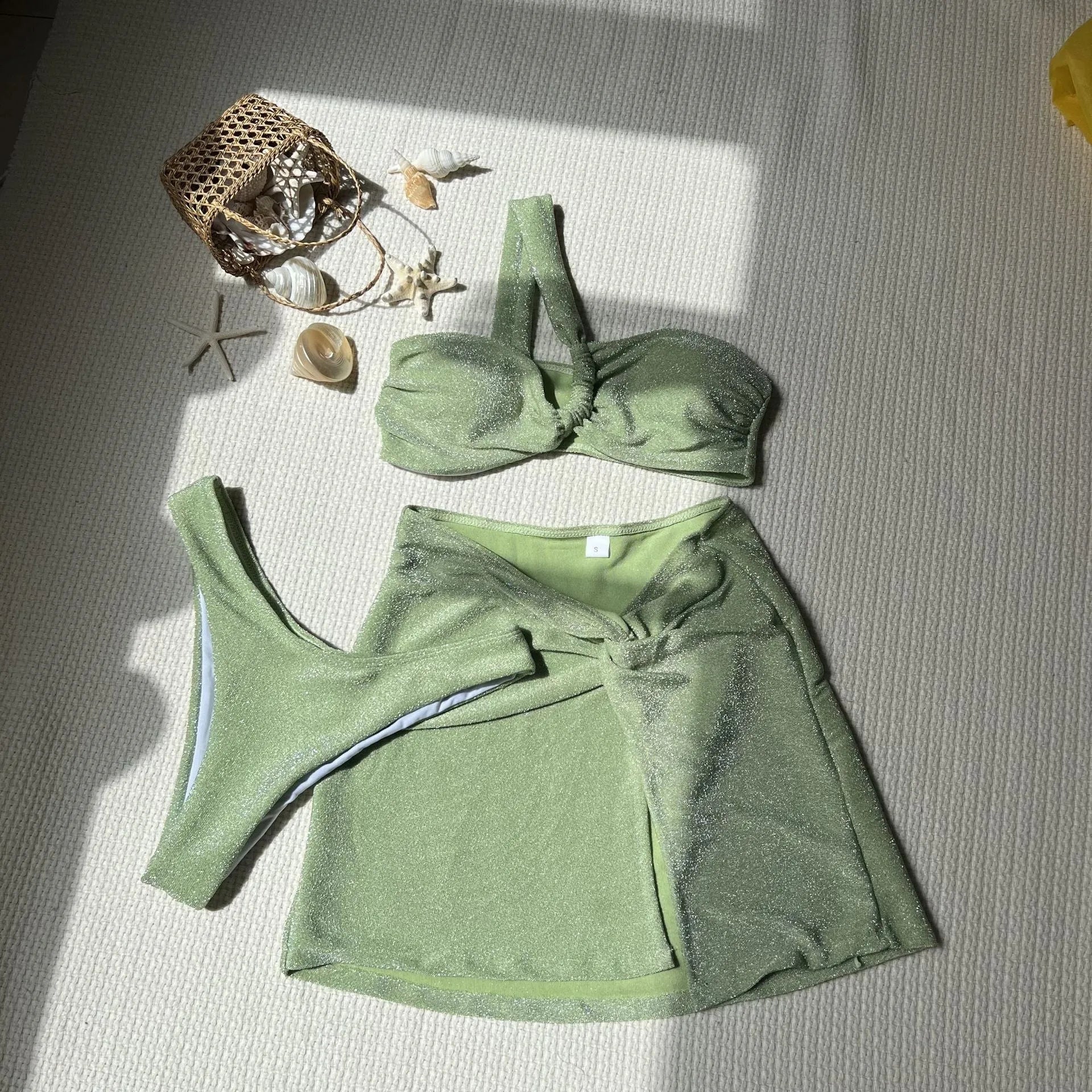 Women's light green one-shoulder tube top swimsuit three-piece set with matching skirt.