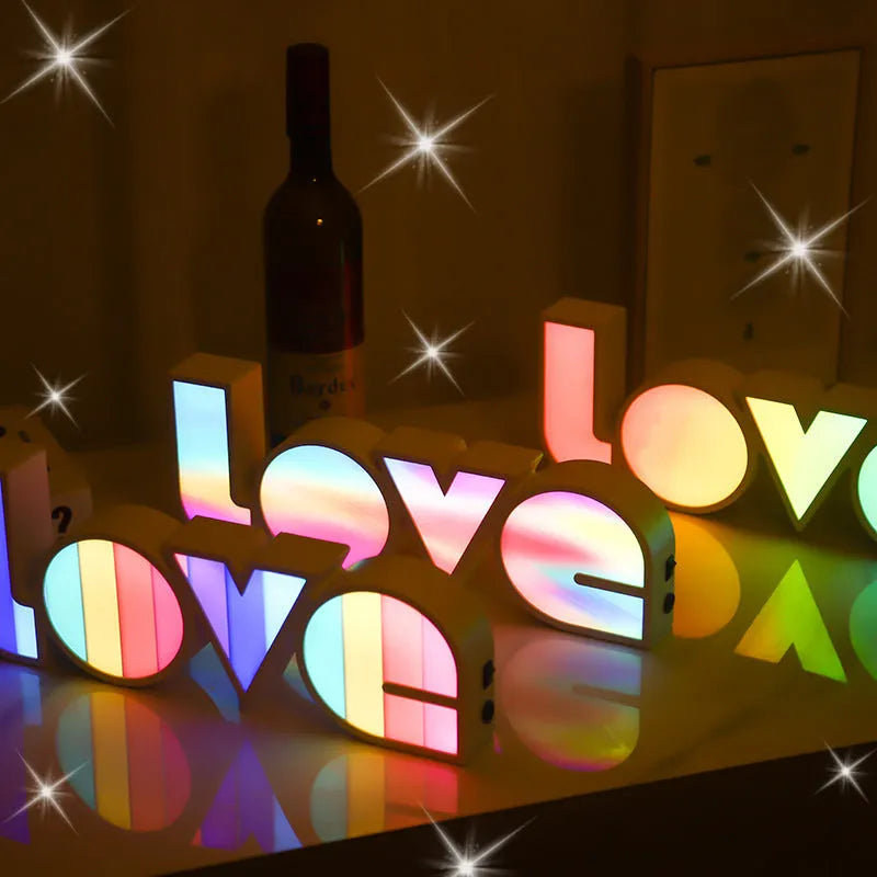 Colourful LED LOVE light decoration with rainbow lampshade on a table.