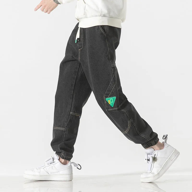 Men's loose-fit tapered cotton trousers in grey shown on a hanger.