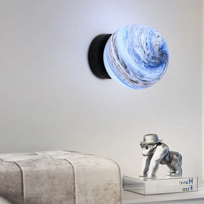 Planet Aisle bedside lamp with painted glass shade in black blue planet colour, on a table