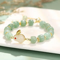 Rabbit charm bracelet with green natural stone beads and gold accents on adjustable chain