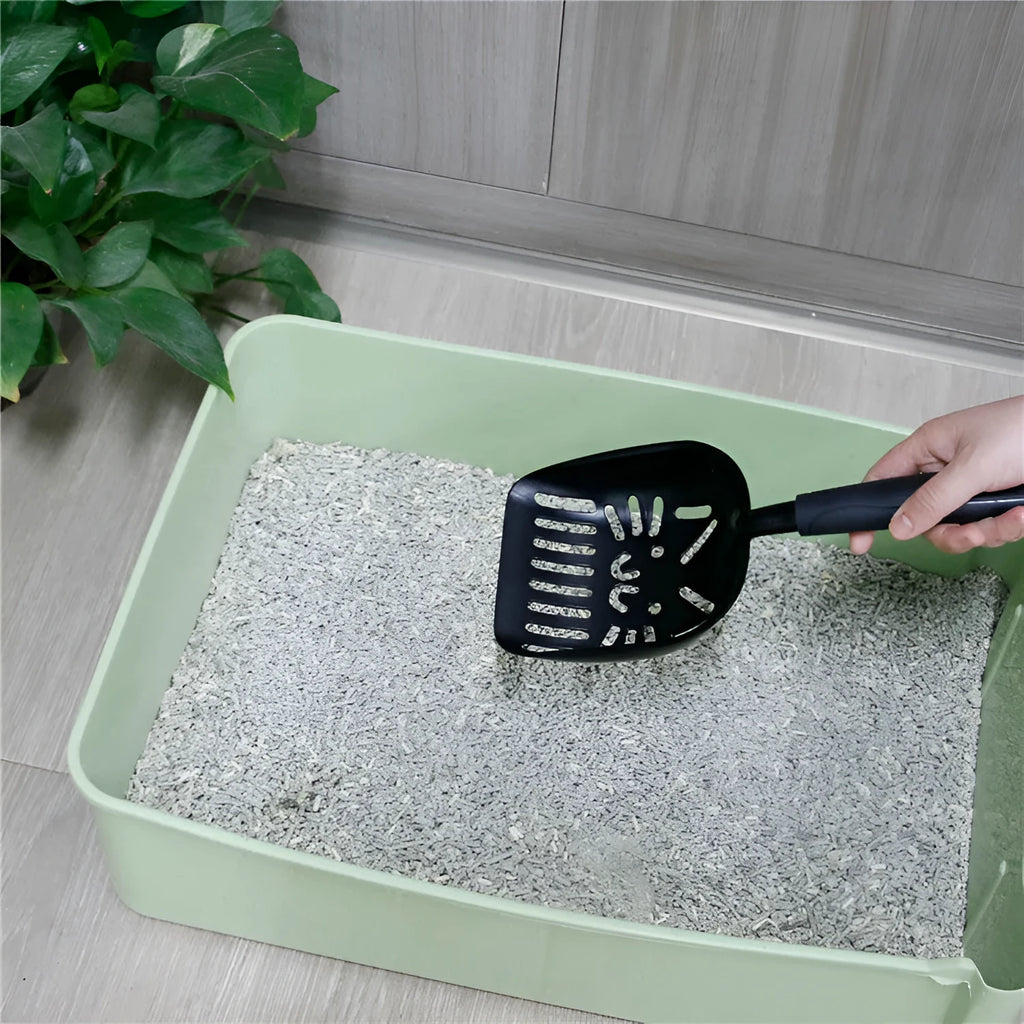 Alloy cat litter scoop with plastic handle on a cat litter box, showing cat face hole design for sifting.