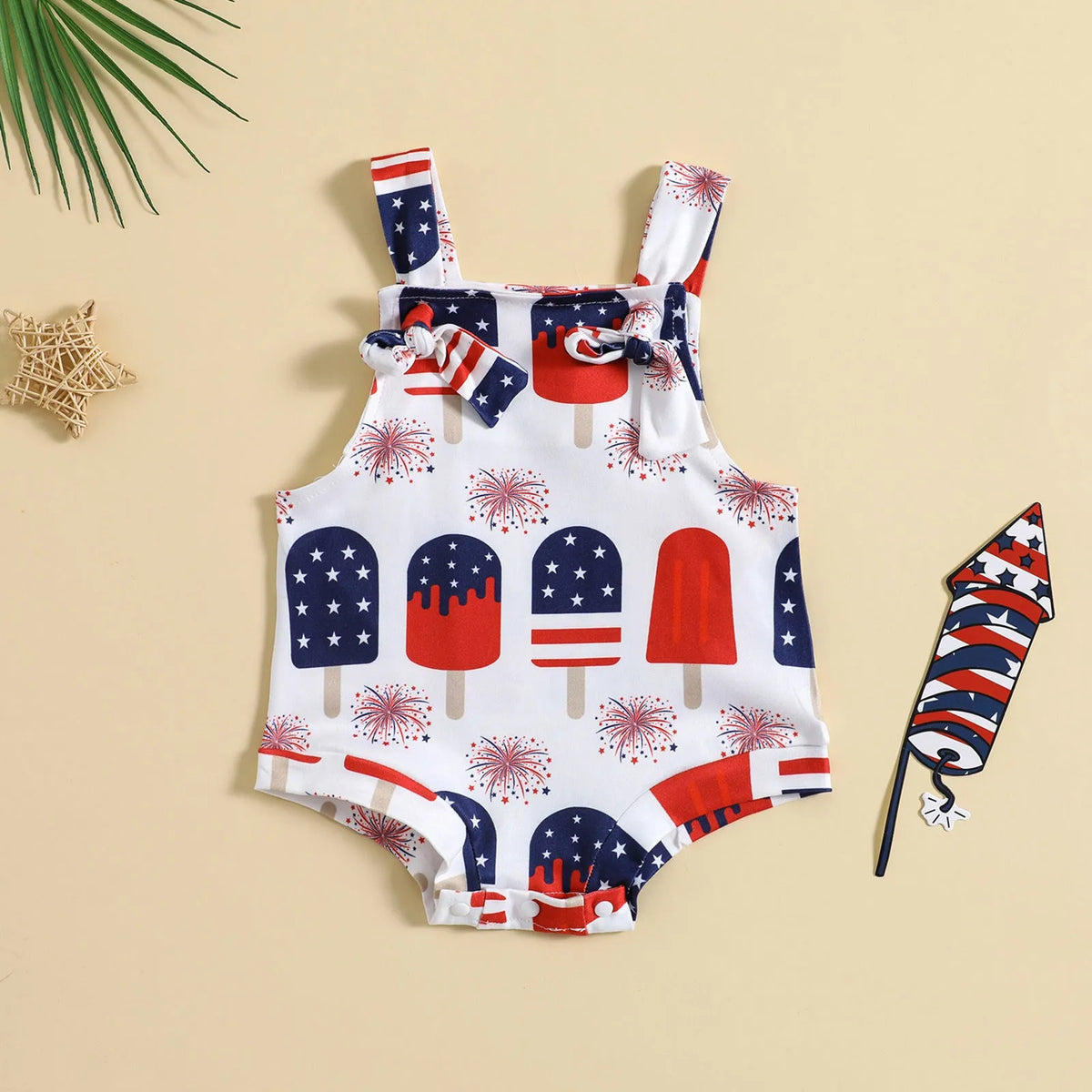 Baby girl wearing a sleeveless knotted front suspender pants jumpsuit in a printed design.