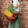 Brown cowhide leather travel crossbody shoulder bag with stitching detail, shown with a laptop and A4 magazine.