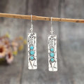Geometric silver earrings with turquoise inlay pattern and retro styling on long strip design