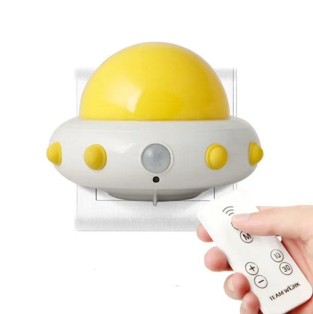 Remote control UFO shaped bedside night light in blue, pink or white colours on a table