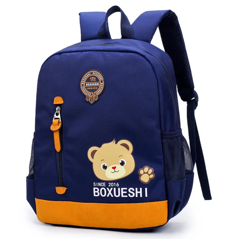 A deep blue children's school bag with a cartoon bear design on the front, showing the front pocket and adjustable straps.