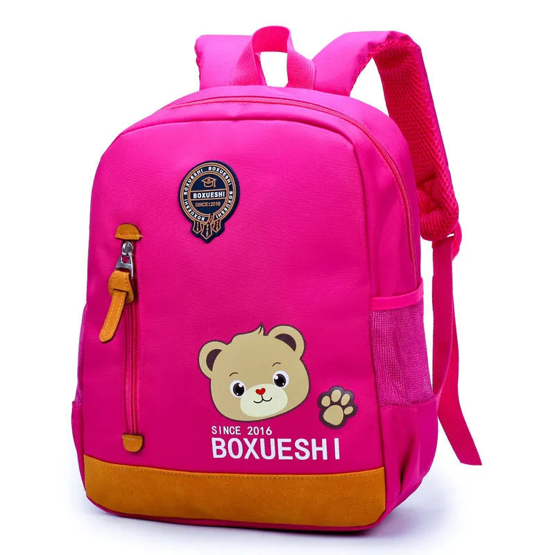 A deep blue children's school bag with a cartoon bear design on the front, showing the front pocket and adjustable straps.