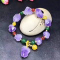 Women's natural shaped violet amethyst bead bracelet with a fu character pendant on a white background.