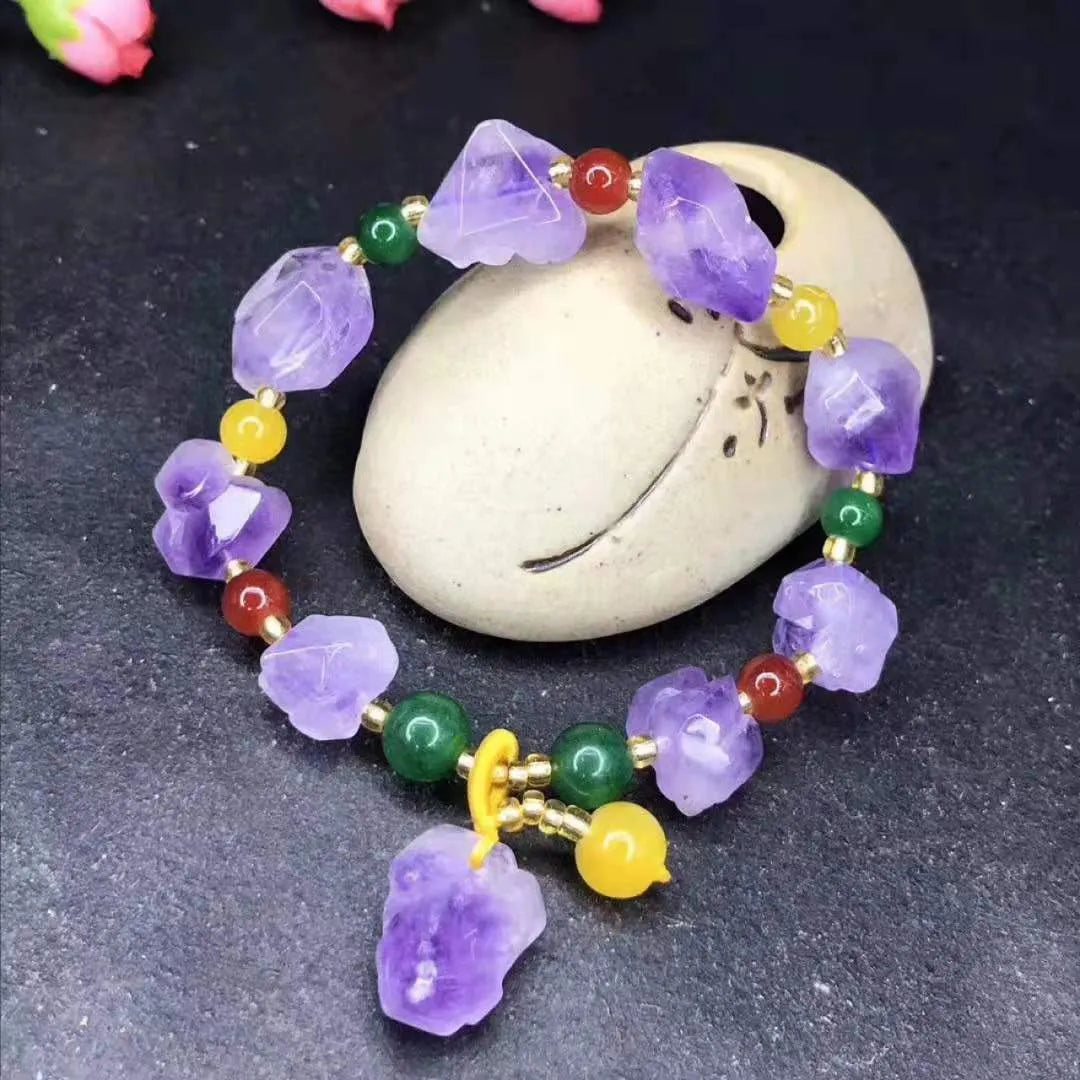 Women's natural shaped violet amethyst bead bracelet with a fu character pendant on a white background.