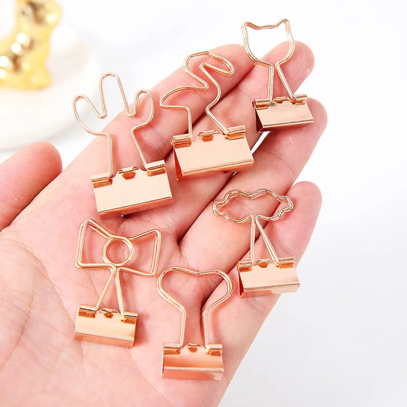 Gold metal decorative paper clip in a bow shape with a long tail design.