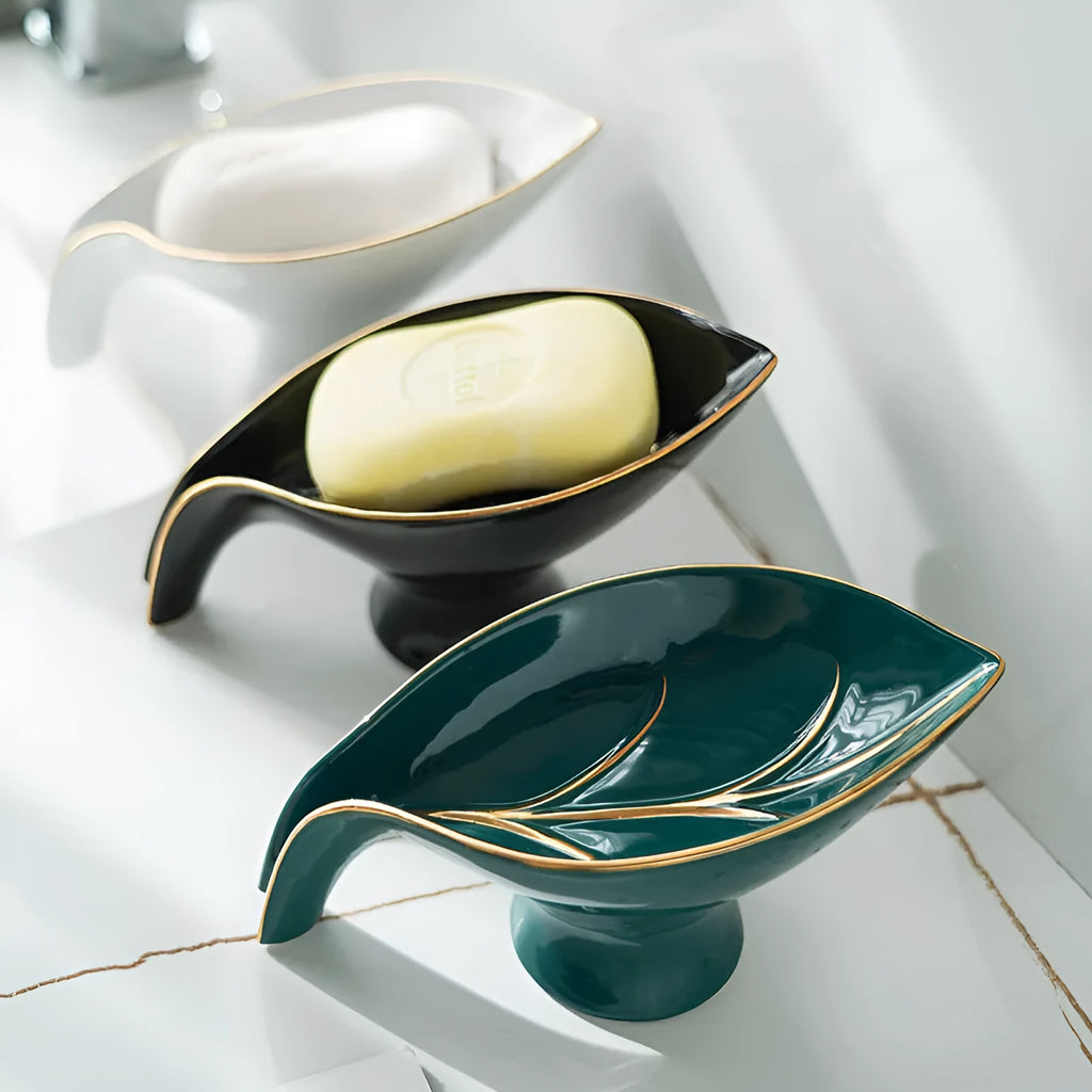 Ceramic leaf shape soap dish with hollow draining base and suction cup, black colour, on bathroom tiles