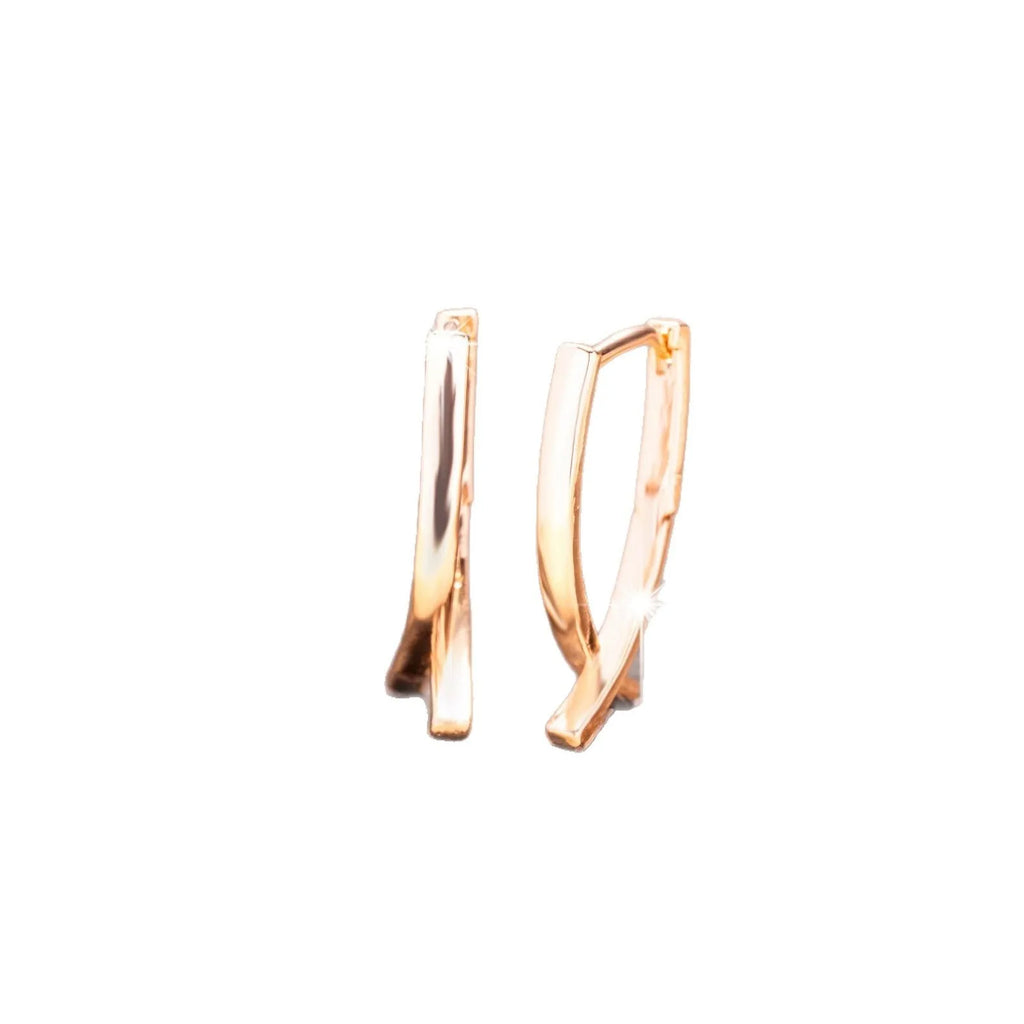A pair of rose gold coloured cross pendant earrings on a copper base.