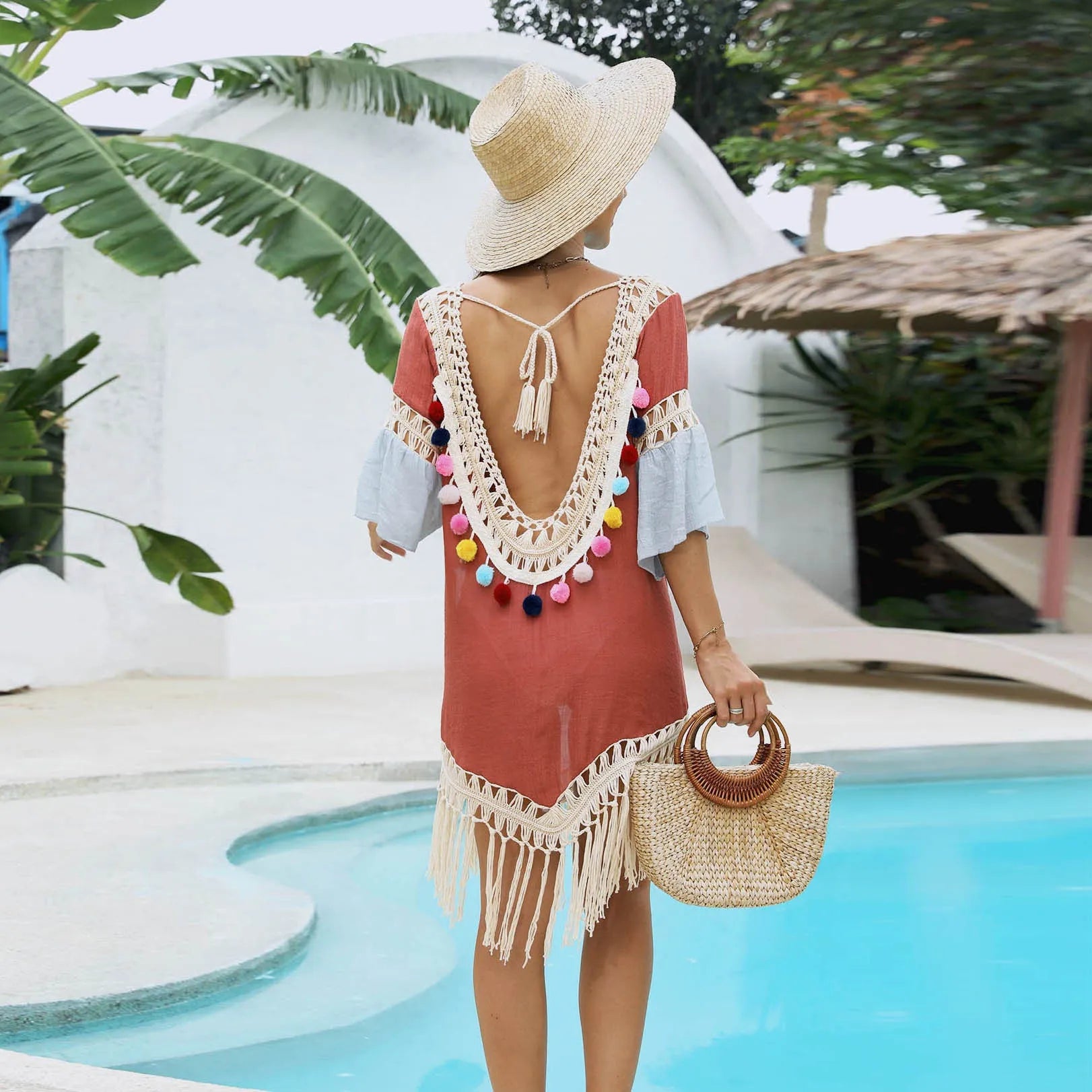 Orange floral pattern beach overskirt with hand crochet detail and tassels, laid flat.