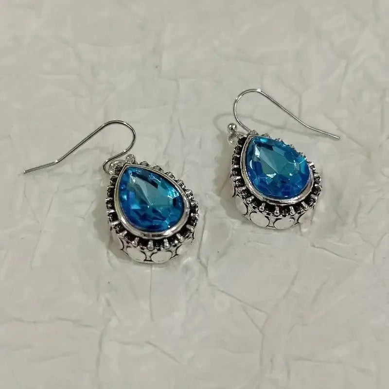 Pair of retro drop-shaped silver alloy earrings with blue gem inlay on white background