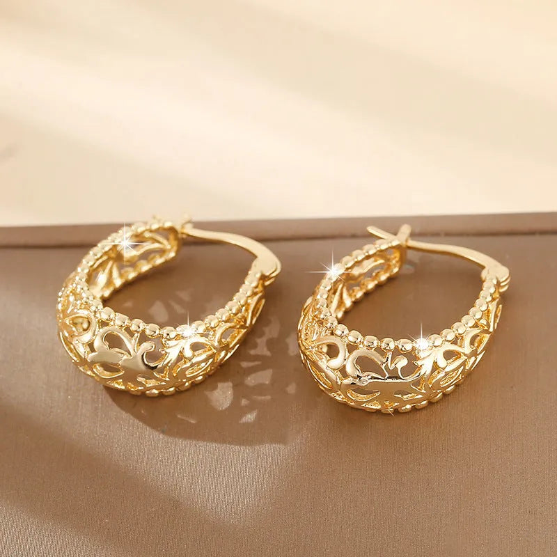Gold copper geometric hollowed-out large earrings with round shape on neutral background