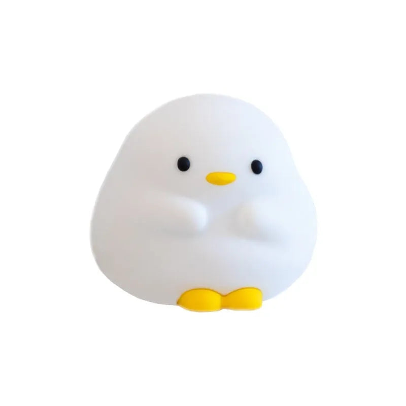 Cute duck shaped LED night lamp with silicone casing and warm light on a bedside table