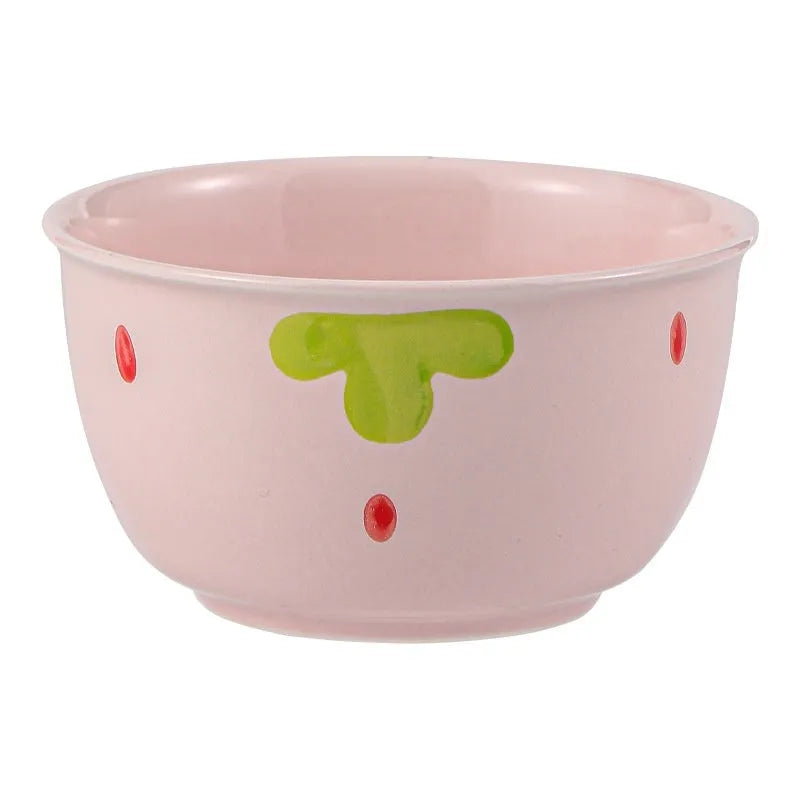 Cute strawberry pattern porcelain dinnerware set with plates, flower bowls, and a twist spoon on a table.
