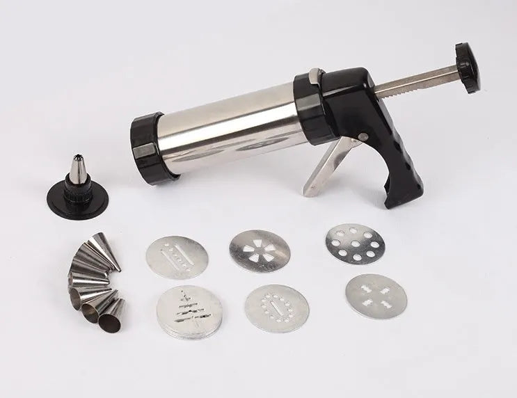 Stainless steel biscuit press gun with assorted cookie moulds and icing nozzles on a baking sheet.