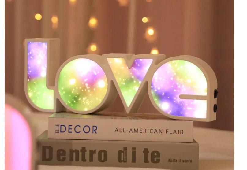 Colourful LED LOVE light decoration with rainbow lampshade on a table.